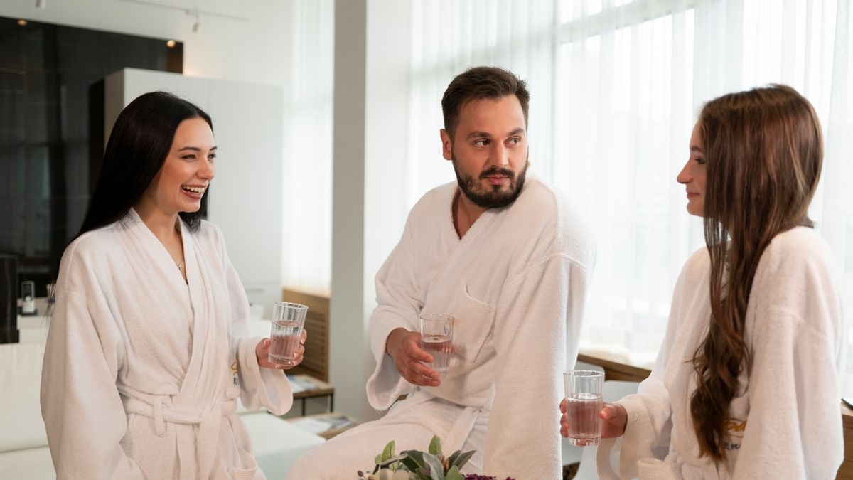 Three adults enjoying a relaxing spa day, chatting and drinking water indoors.